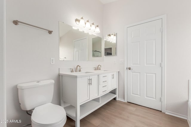 full bathroom with a sink, toilet, wood finished floors, and double vanity