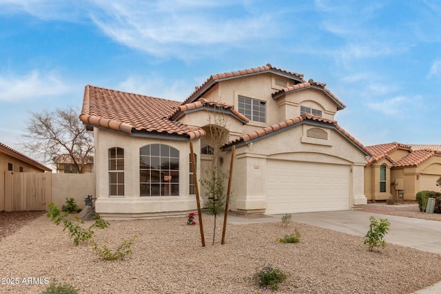 mediterranean / spanish-style house with a tiled roof, fence, driveway, and stucco siding