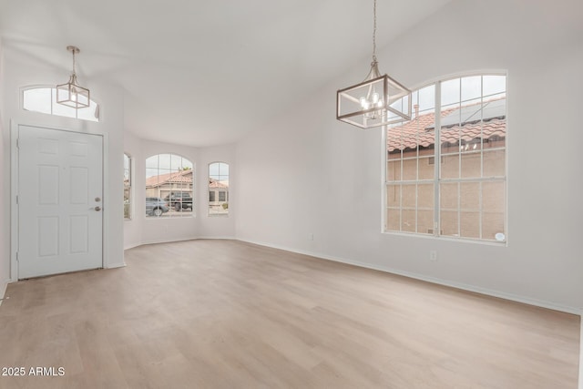 entryway with baseboards, an inviting chandelier, wood finished floors, and vaulted ceiling