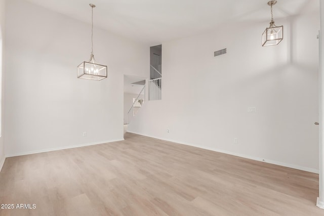 unfurnished dining area with visible vents, baseboards, a chandelier, and light wood finished floors