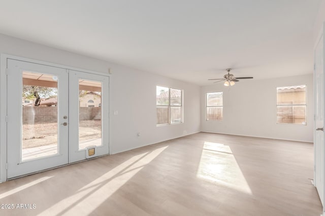 unfurnished room with french doors, plenty of natural light, light wood-style flooring, and a ceiling fan