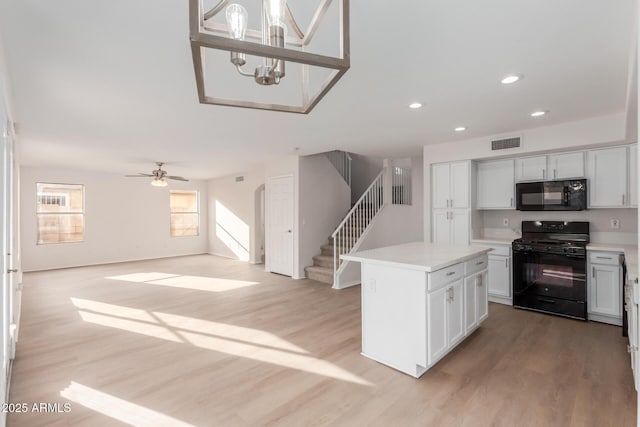 kitchen with light wood-type flooring, visible vents, black appliances, and light countertops