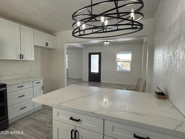 kitchen featuring light stone counters, a chandelier, pendant lighting, and white cabinetry