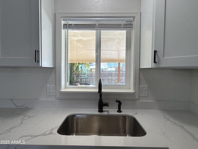 kitchen featuring light stone counters and a sink