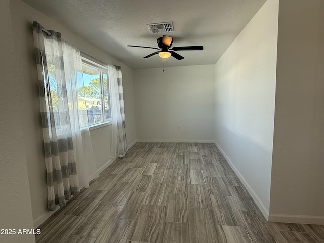 empty room with baseboards, wood finished floors, visible vents, and a textured ceiling