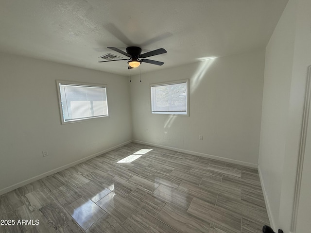 spare room with visible vents, baseboards, a textured ceiling, and ceiling fan