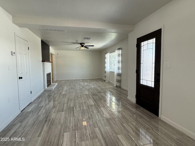 unfurnished living room with visible vents, baseboards, a brick fireplace, and a ceiling fan