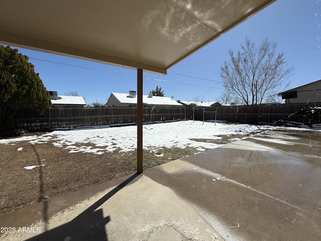 snowy yard with a fenced backyard and a patio area