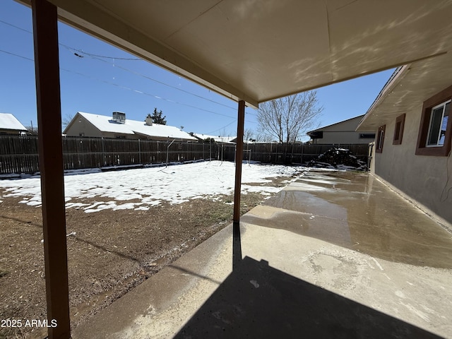 snowy yard featuring a patio and a fenced backyard