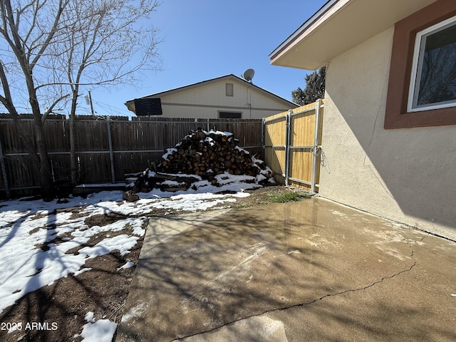 yard layered in snow featuring a patio and a fenced backyard