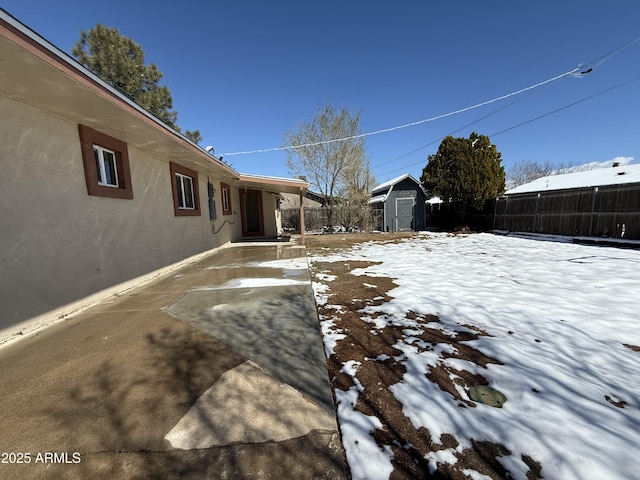 snowy yard with an outdoor structure, a shed, and fence