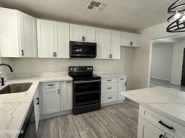 kitchen with visible vents, light stone countertops, range with two ovens, white cabinets, and a sink