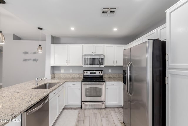 8341 W Cypress St, Phoenix, AZ 85037 - kitchen with stainless steel appliances, white cabinetry, light stone counters, recessed lighting, and pendant lighting