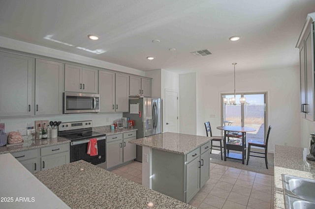 kitchen featuring pendant lighting, gray cabinets, a kitchen island, stainless steel appliances, and light tile patterned flooring