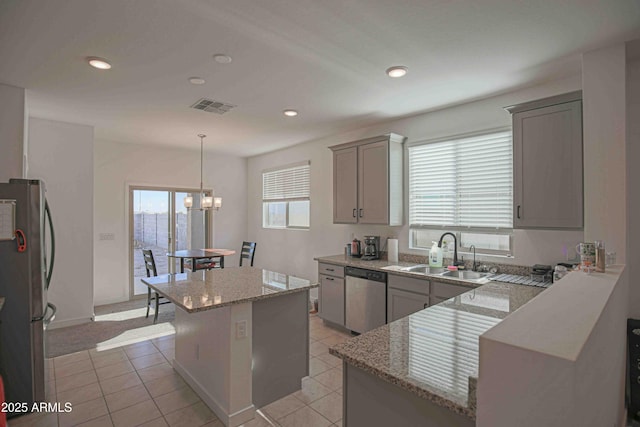 kitchen with sink, gray cabinetry, stainless steel appliances, a center island, and decorative light fixtures