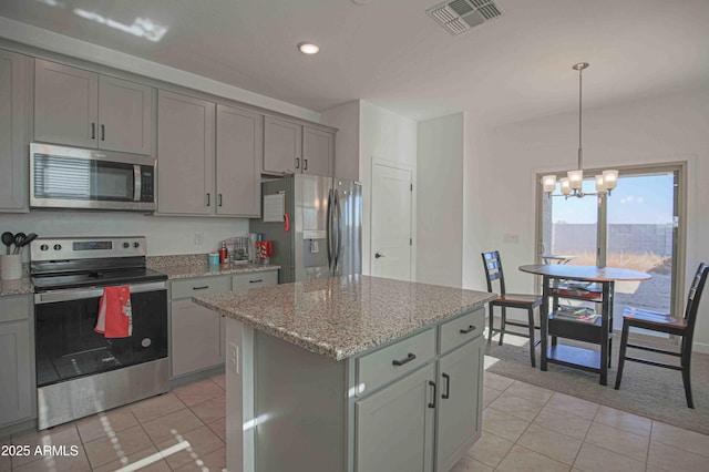 kitchen with light tile patterned flooring, stainless steel appliances, a center island, and pendant lighting