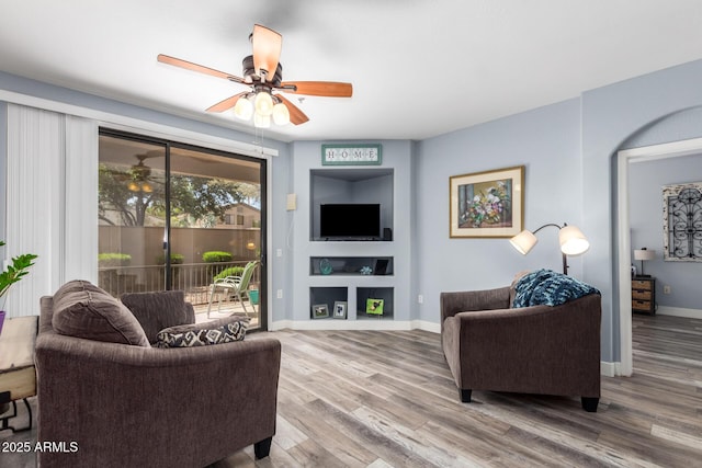 living area with a ceiling fan, baseboards, and wood finished floors