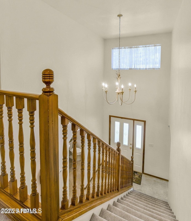 stairs featuring a high ceiling, carpet floors, and an inviting chandelier