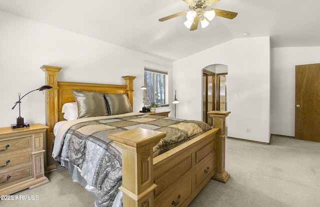bedroom featuring light colored carpet, vaulted ceiling, baseboards, arched walkways, and ceiling fan