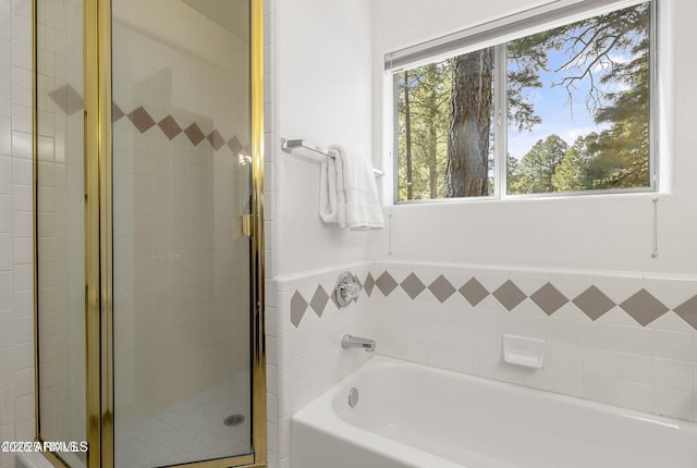 bathroom featuring a garden tub and a shower stall