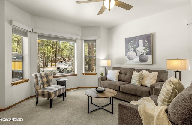 living area featuring baseboards, ceiling fan, carpet, and a healthy amount of sunlight