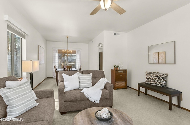living room featuring light carpet, ceiling fan with notable chandelier, visible vents, and baseboards