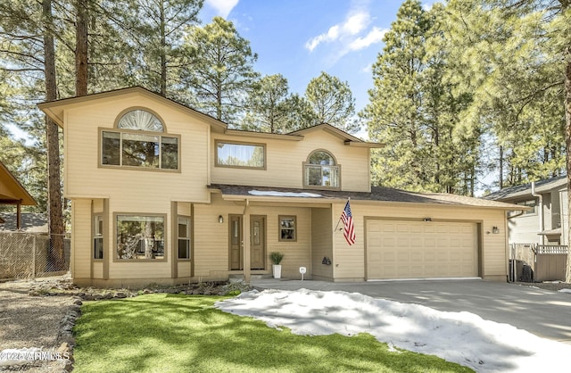 view of front of home with driveway, an attached garage, fence, and a front yard