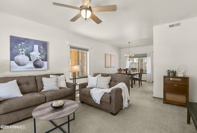 living area with light colored carpet, visible vents, and ceiling fan with notable chandelier