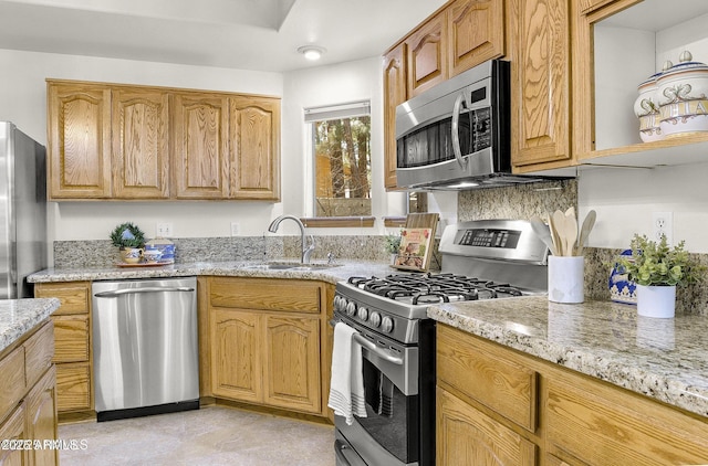kitchen with light stone counters, a sink, and stainless steel appliances