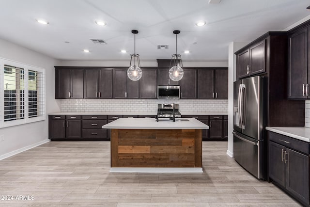 kitchen with stainless steel appliances, hanging light fixtures, a kitchen island with sink, and dark brown cabinetry