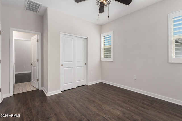 unfurnished bedroom featuring ceiling fan, dark hardwood / wood-style flooring, and a closet