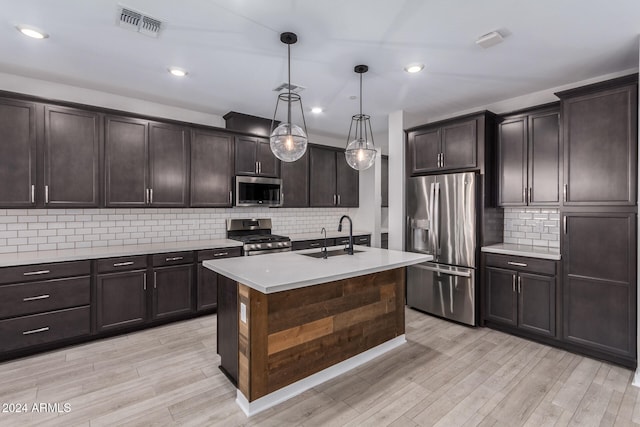 kitchen with dark brown cabinets, stainless steel appliances, sink, and hanging light fixtures