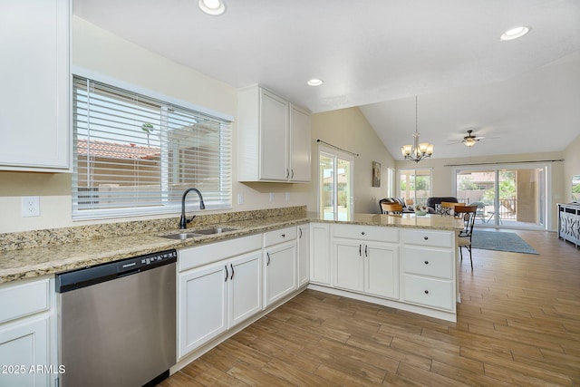 kitchen featuring dishwasher, a sink, open floor plan, white cabinets, and a peninsula
