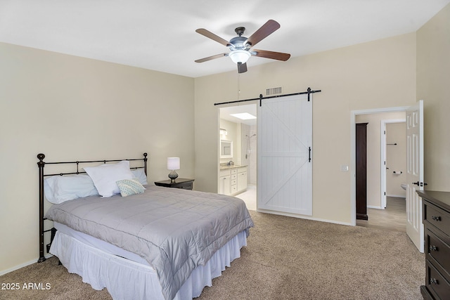 carpeted bedroom with a barn door, baseboards, connected bathroom, and ceiling fan