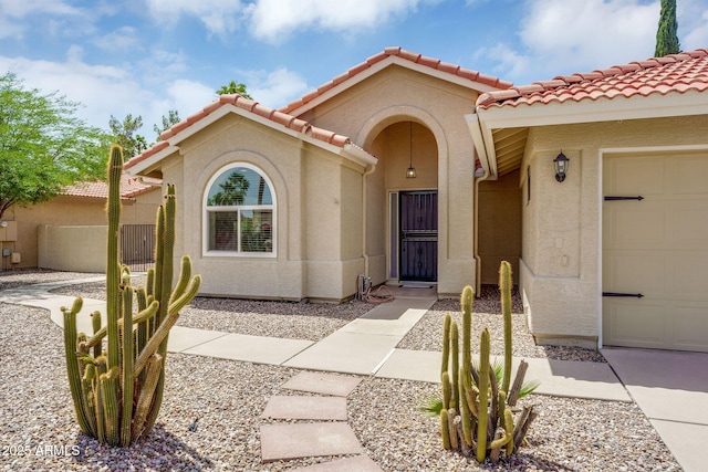 view of front facade with a tile roof, stucco siding, a garage, and fence