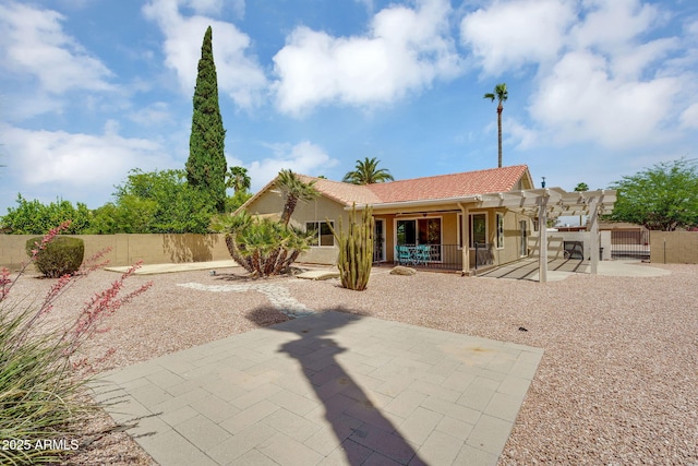 rear view of house featuring a pergola, a patio area, a tiled roof, stucco siding, and a fenced backyard