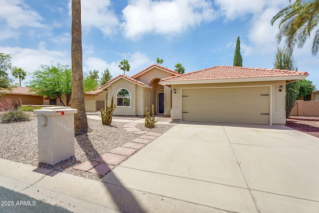 mediterranean / spanish house featuring concrete driveway, stucco siding, a tiled roof, and an attached garage