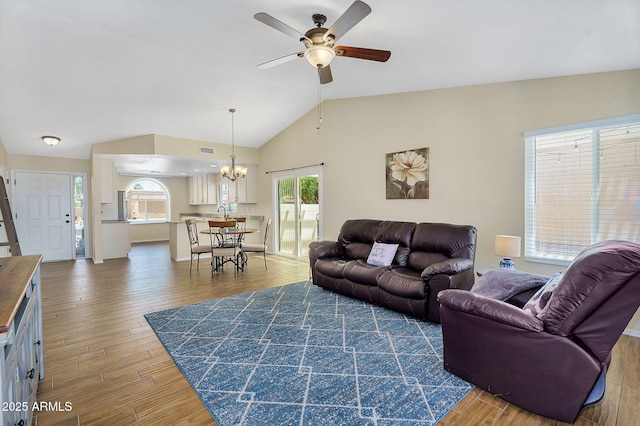 living area featuring a ceiling fan, a chandelier, wood finished floors, and vaulted ceiling