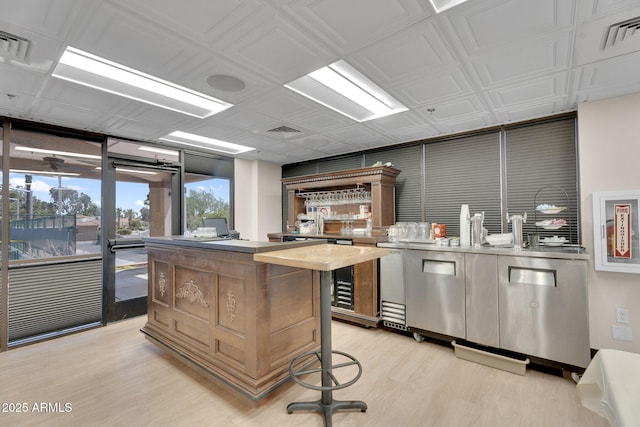 kitchen featuring a kitchen island, light wood finished floors, wine cooler, and light countertops