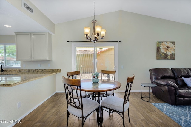 dining space featuring a chandelier, vaulted ceiling, dark wood-style flooring, and baseboards