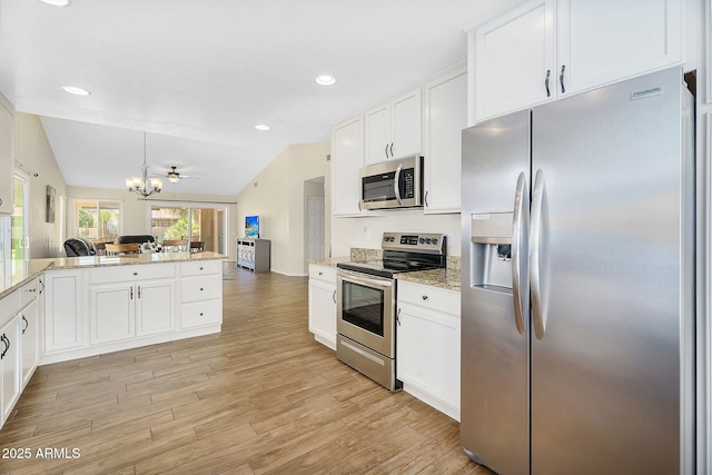 kitchen with appliances with stainless steel finishes, white cabinets, a chandelier, light wood-style floors, and open floor plan