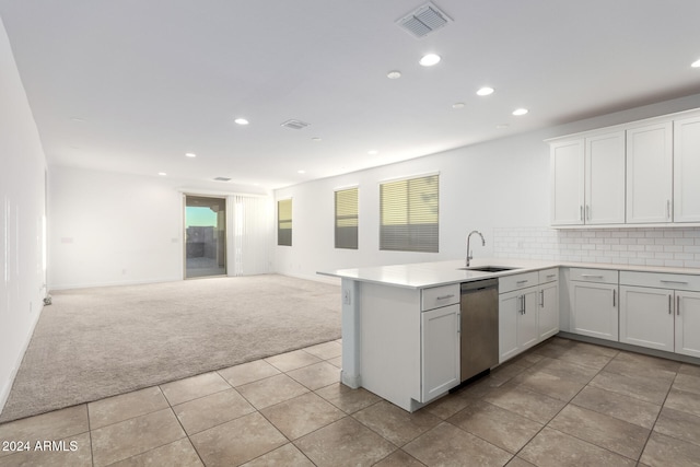 kitchen featuring sink, kitchen peninsula, light colored carpet, and dishwasher