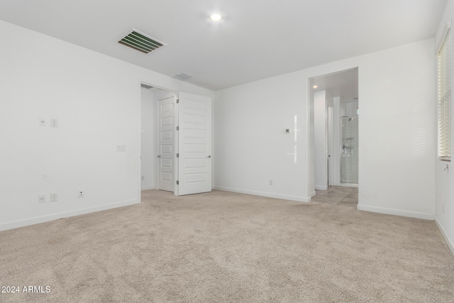 unfurnished bedroom with light carpet and connected bathroom