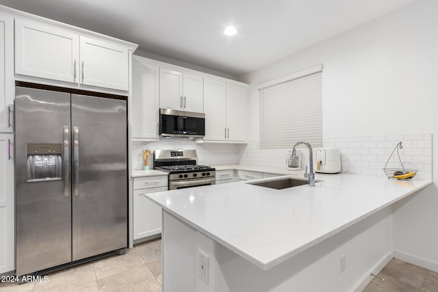 kitchen featuring tasteful backsplash, sink, kitchen peninsula, white cabinetry, and stainless steel appliances