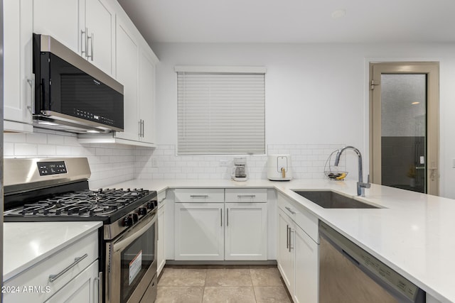 kitchen with sink, light tile patterned flooring, stainless steel appliances, white cabinets, and decorative backsplash