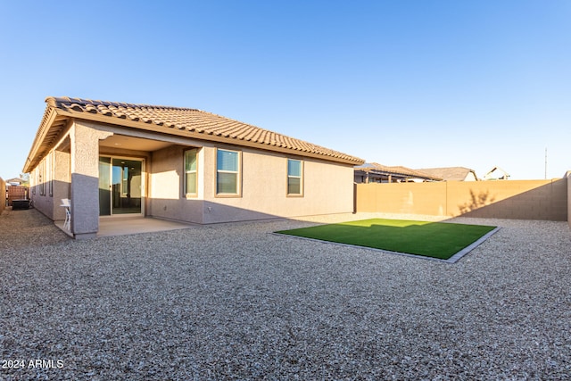 back of house with a patio and a lawn