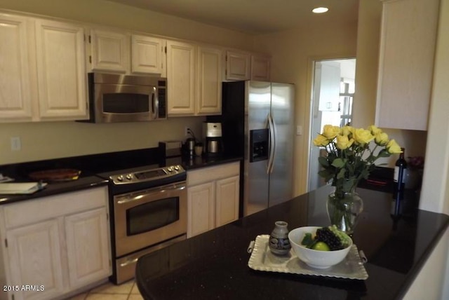 kitchen featuring dark countertops, light tile patterned floors, recessed lighting, stainless steel appliances, and white cabinetry