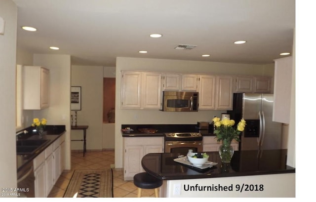 kitchen featuring dark countertops, visible vents, appliances with stainless steel finishes, and a sink