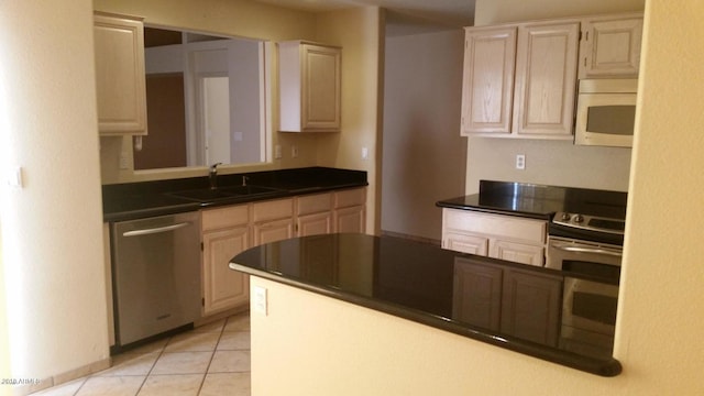 kitchen featuring a sink, dark countertops, appliances with stainless steel finishes, and light tile patterned floors