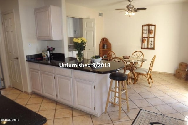 kitchen with light tile patterned flooring, visible vents, a peninsula, and dark countertops